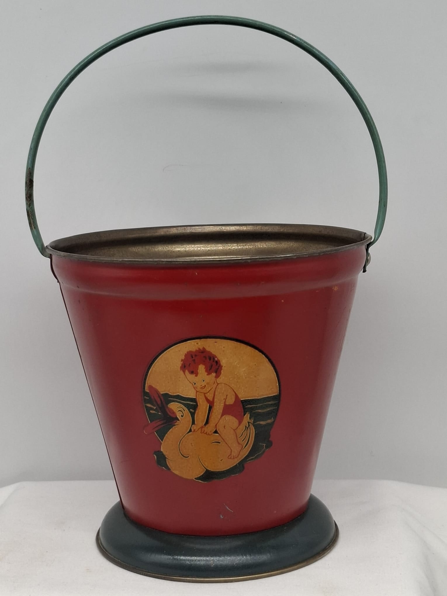 Early 20th Century Lithographed Tin Sand Pail – From Extensive European Collection: A charming and increasingly scarce early 20th century lithographed tin sand pail, exemplifying the colorful and imaginative design of classic seaside toys. This piece features vibrant period lithograp