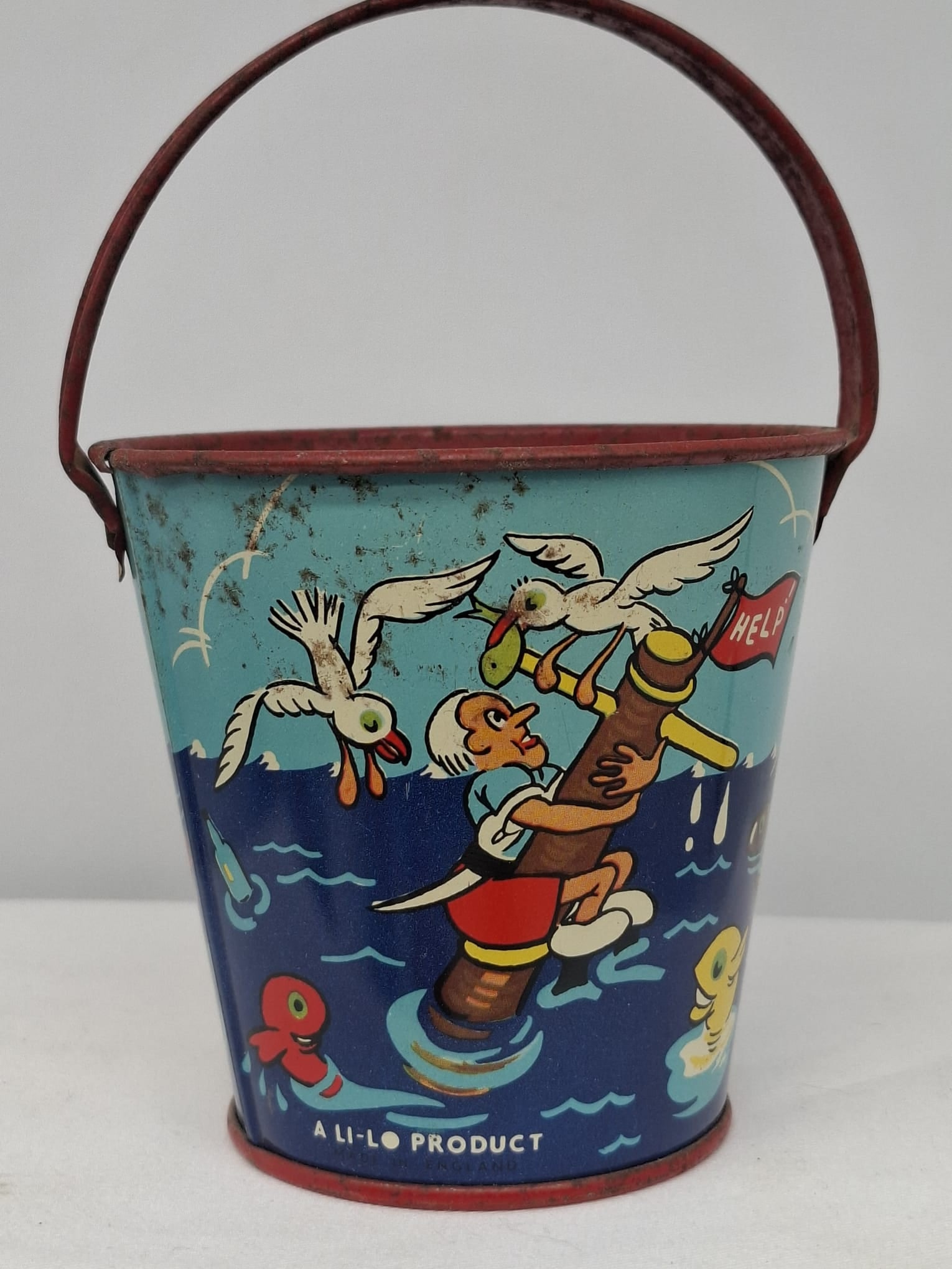 Early 20th Century Lithographed Tin Sand Pail – From Extensive European Collection: A charming and increasingly scarce early 20th century lithographed tin sand pail, exemplifying the colorful and imaginative design of classic seaside toys. This piece features vibrant period lithograp