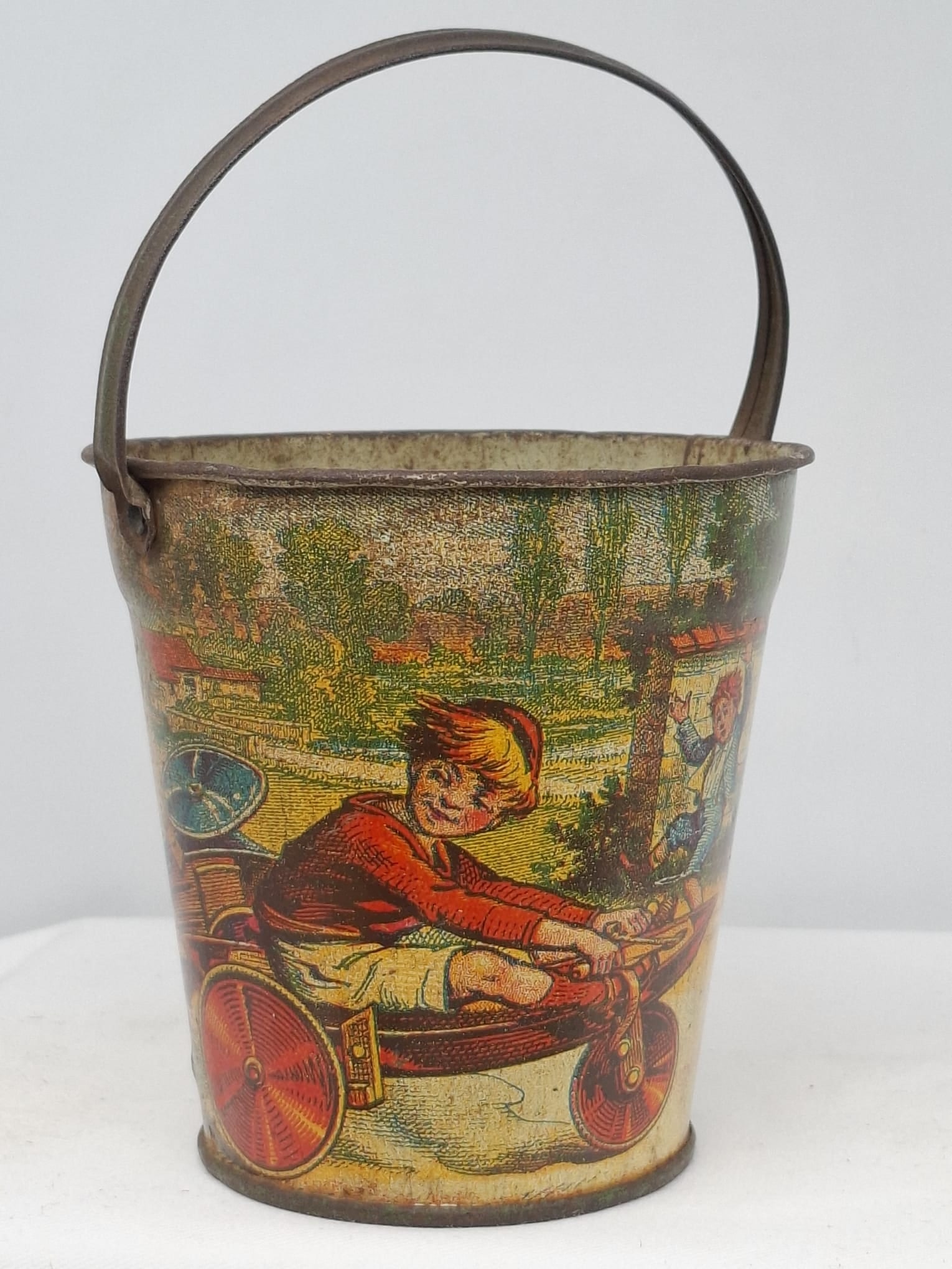 Early 20th Century Lithographed Tin Sand Pail – From Extensive European Collection: A charming and increasingly scarce early 20th century lithographed tin sand pail, exemplifying the colorful and imaginative design of classic seaside toys. This piece features vibrant period lithograp