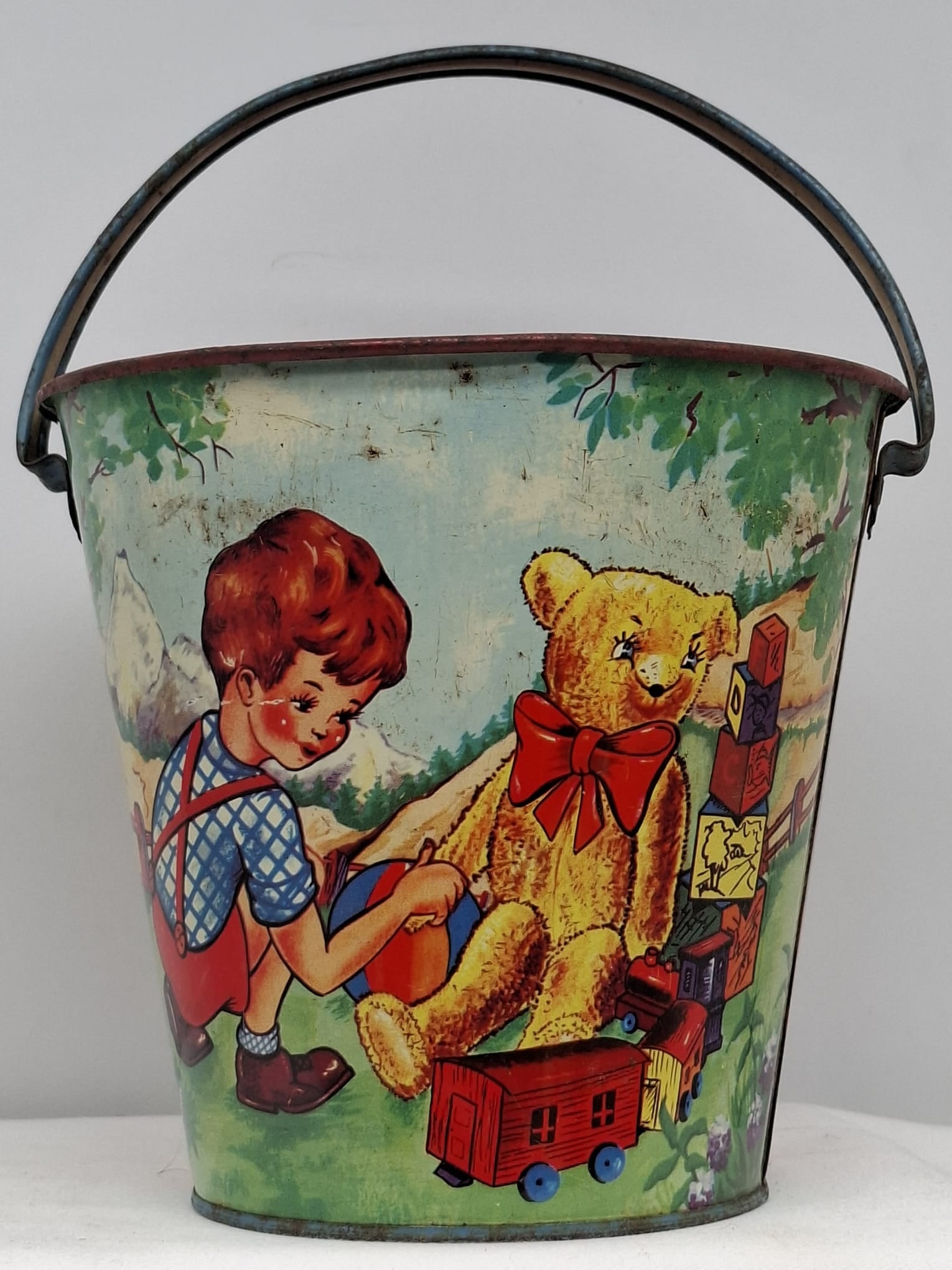 Early 20th Century Lithographed Tin Sand Pail – From Extensive European Collection: A charming and increasingly scarce early 20th century lithographed tin sand pail, exemplifying the colorful and imaginative design of classic seaside toys. This piece features vibrant period lithograp
