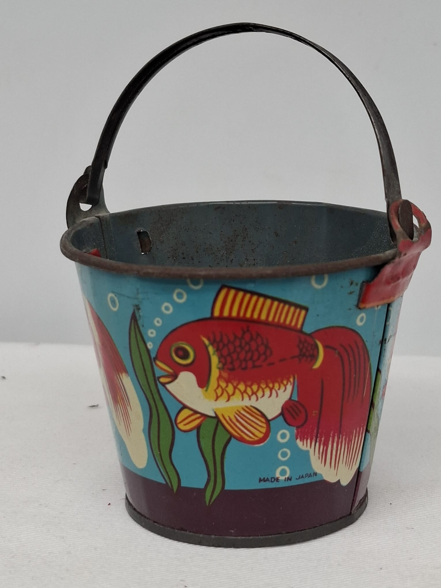 Early 20th Century Lithographed Tin Sand Pail – From Extensive European Collection: A charming and increasingly scarce early 20th century lithographed tin sand pail, exemplifying the colorful and imaginative design of classic seaside toys. This piece features vibrant period lithograp