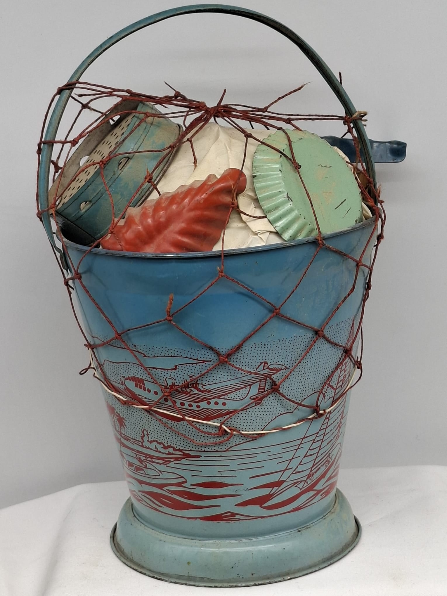 Early 20th Century Lithographed Tin Sand Pail – From Extensive European Collection: A charming and increasingly scarce early 20th century lithographed tin sand pail, exemplifying the colorful and imaginative design of classic seaside toys. This piece features vibrant period lithograp