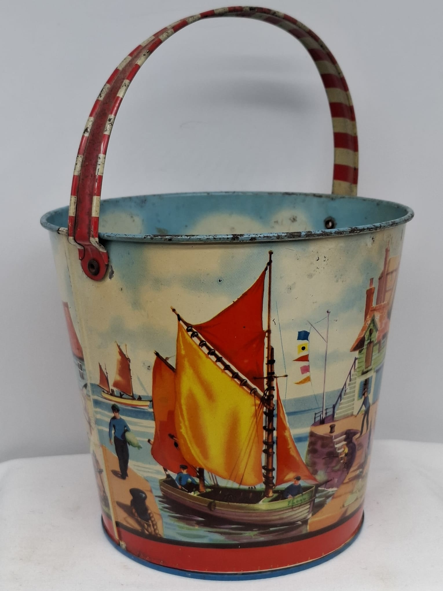 Early 20th Century Lithographed Tin Sand Pail – From Extensive European Collection: A charming and increasingly scarce early 20th century lithographed tin sand pail, exemplifying the colorful and imaginative design of classic seaside toys. This piece features vibrant period lithograp