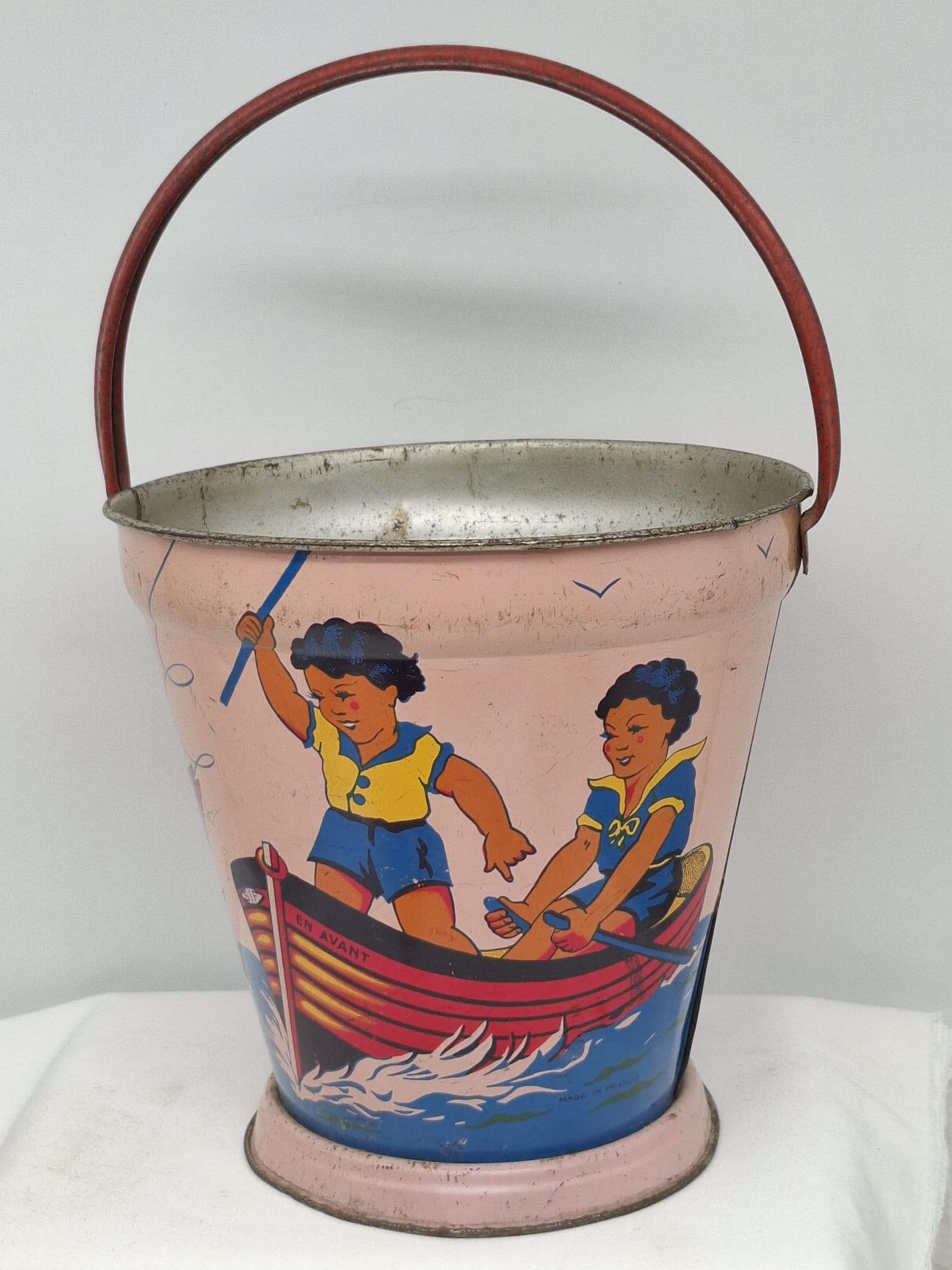 Early 20th Century Lithographed Tin Sand Pail – From Extensive European Collection: A charming and increasingly scarce early 20th century lithographed tin sand pail, exemplifying the colorful and imaginative design of classic seaside toys. This piece features vibrant period lithograp