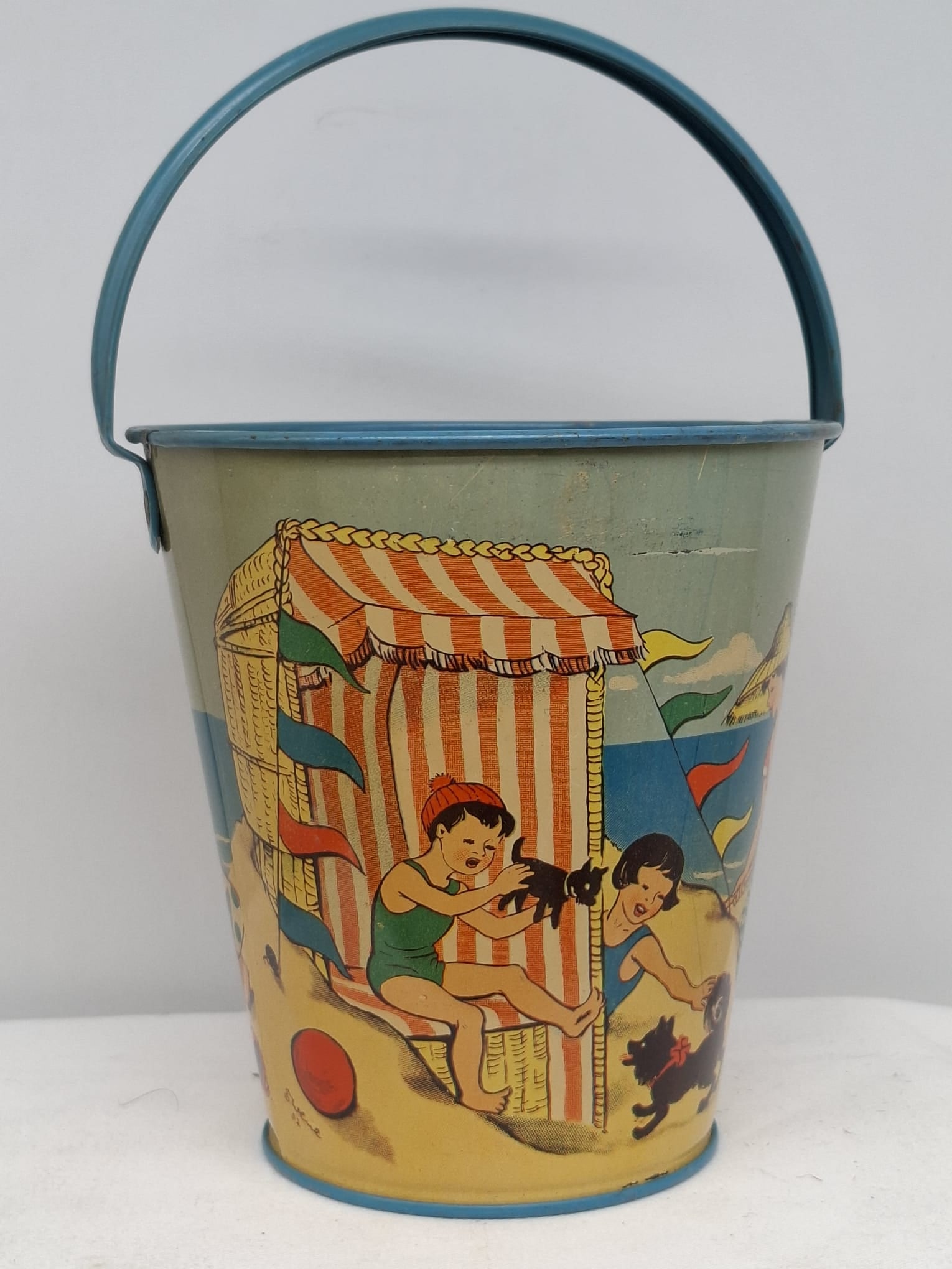Early 20th Century Lithographed Tin Sand Pail – From Extensive European Collection: A charming and increasingly scarce early 20th century lithographed tin sand pail, exemplifying the colorful and imaginative design of classic seaside toys. This piece features vibrant period lithograp