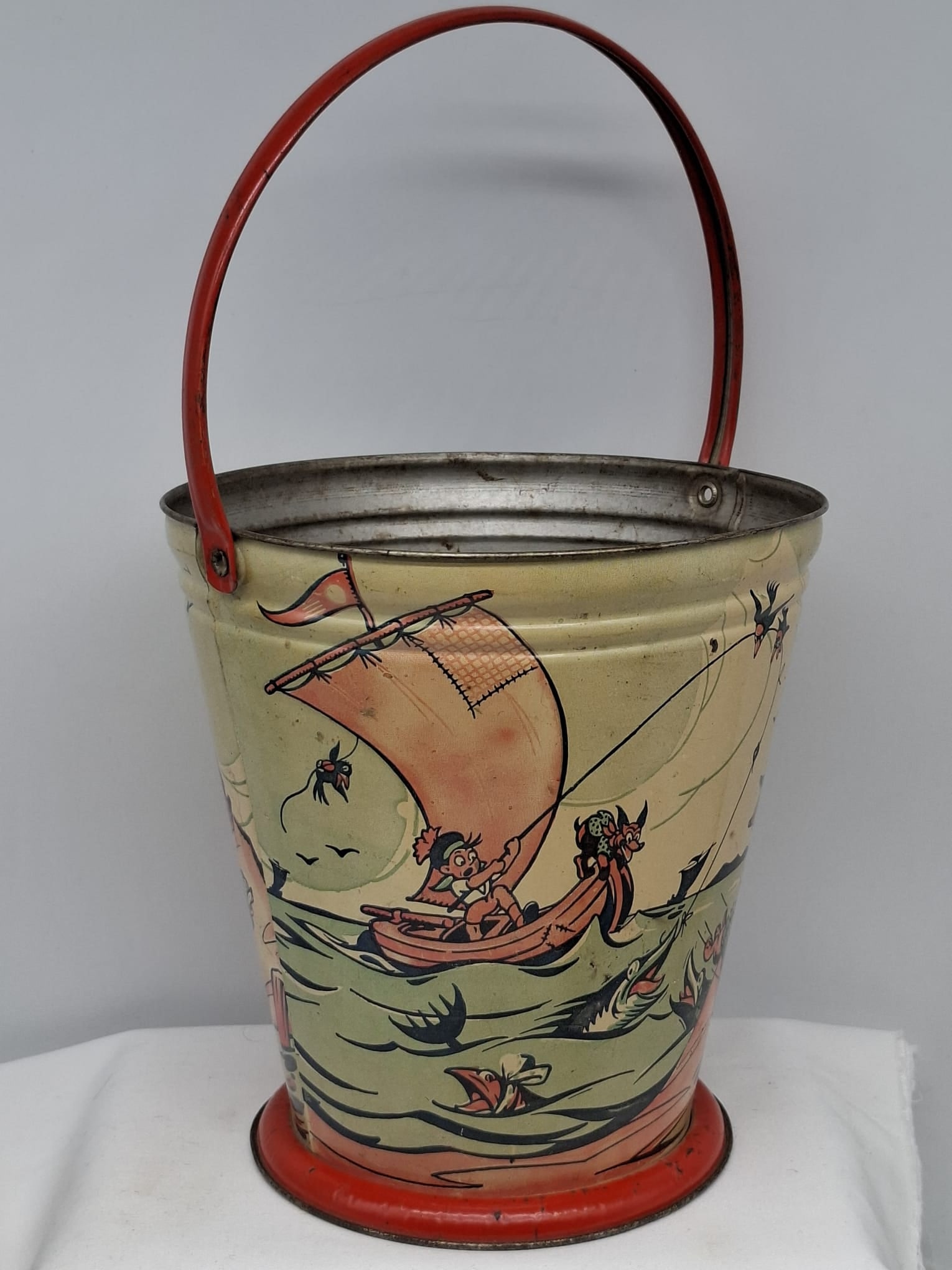 Early 20th Century Lithographed Tin Sand Pail – From Extensive European Collection: A charming and increasingly scarce early 20th century lithographed tin sand pail, exemplifying the colorful and imaginative design of classic seaside toys. This piece features vibrant period lithograp
