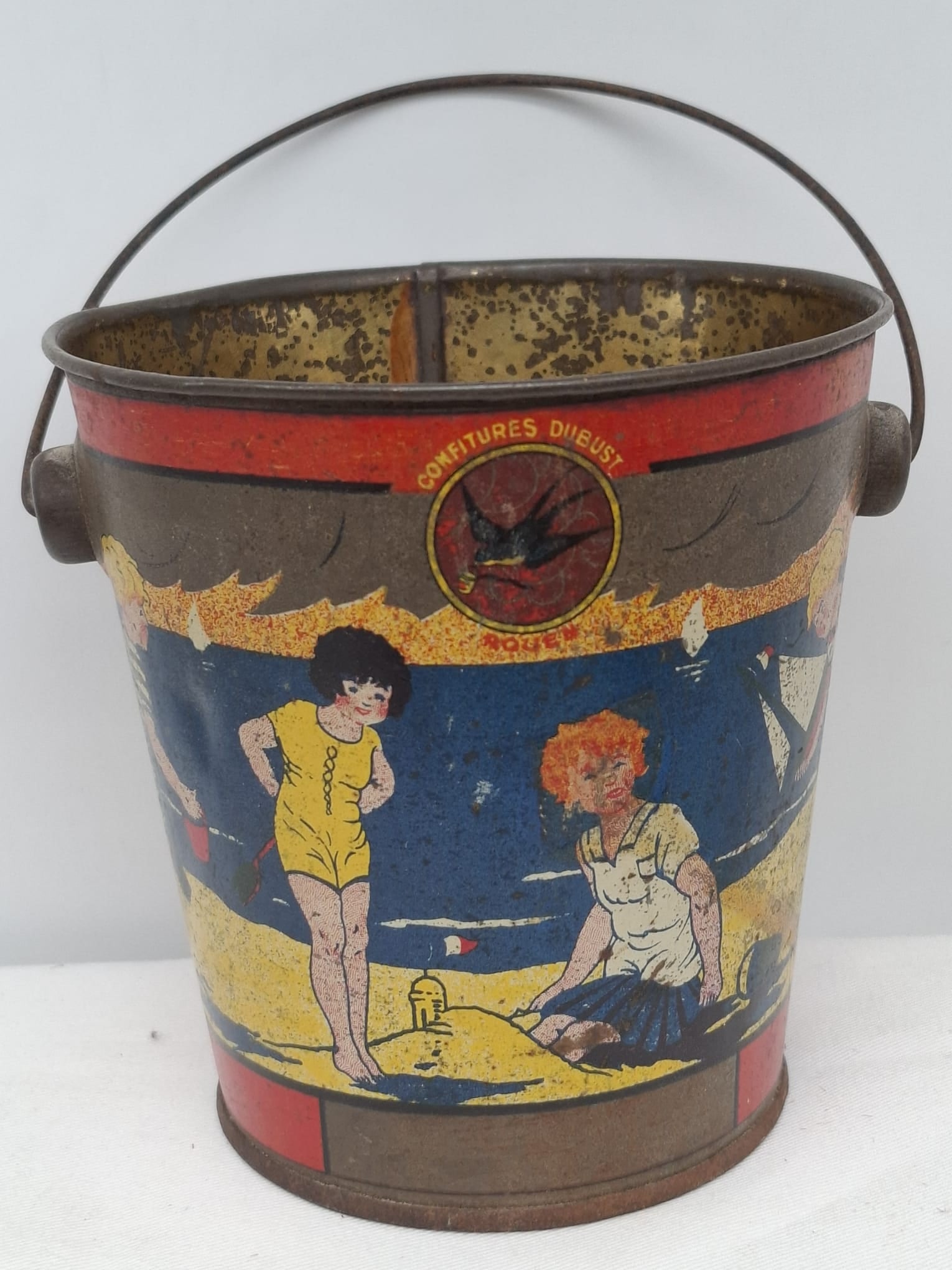 Early 20th Century Lithographed Tin Sand Pail – From Extensive European Collection: A charming and increasingly scarce early 20th century lithographed tin sand pail, exemplifying the colorful and imaginative design of classic seaside toys. This piece features vibrant period lithograp