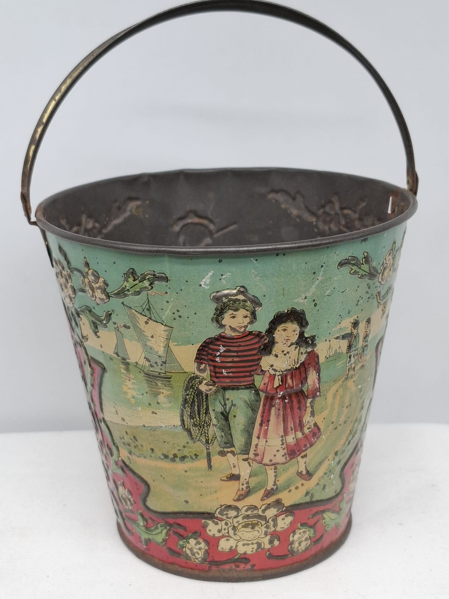 Early 20th Century Lithographed Tin Sand Pail – From Extensive European Collection: A charming and increasingly scarce early 20th century lithographed tin sand pail, exemplifying the colorful and imaginative design of classic seaside toys. This piece features vibrant period lithograp