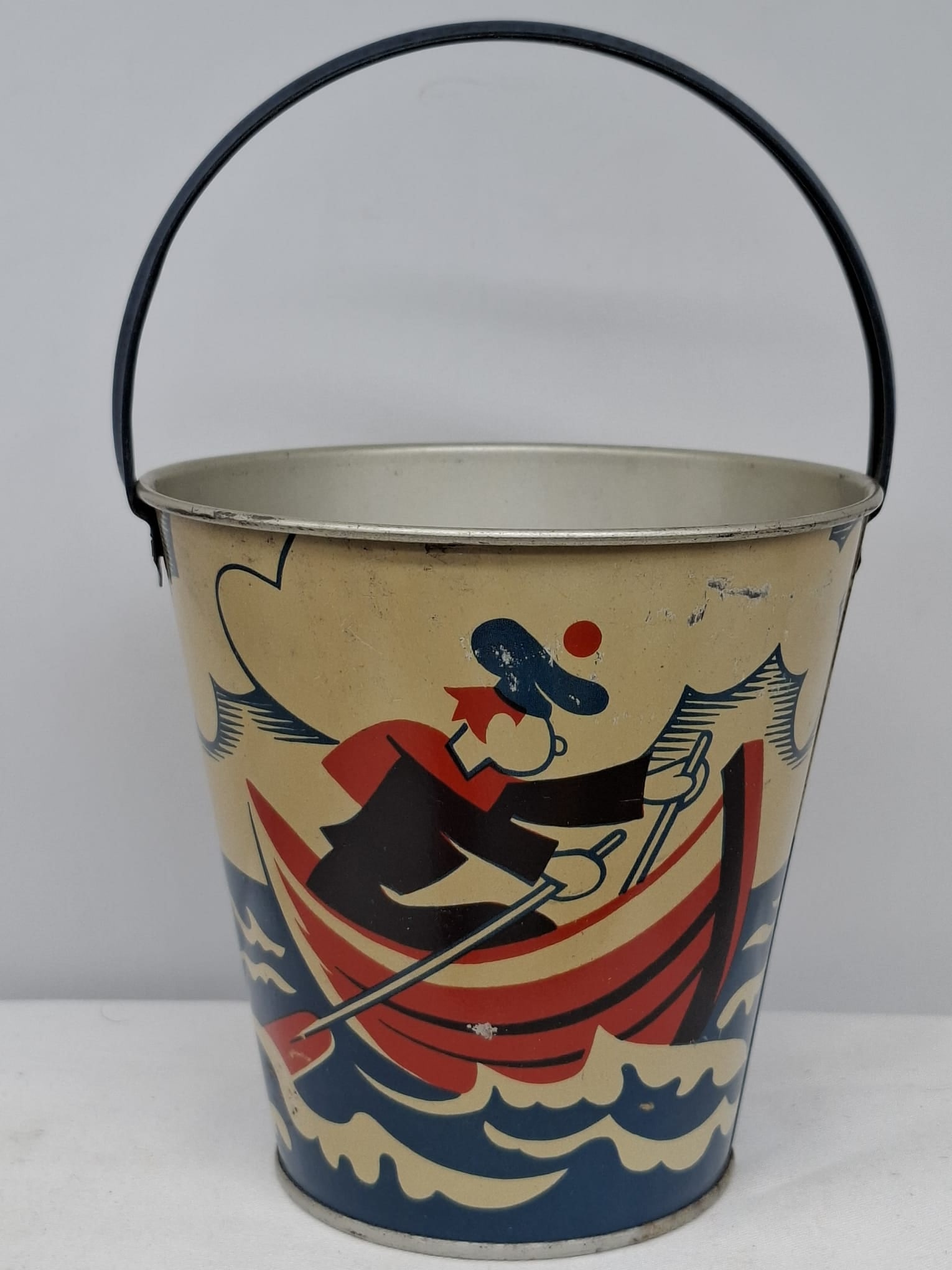Early 20th Century Lithographed Tin Sand Pail – From Extensive European Collection: A charming and increasingly scarce early 20th century lithographed tin sand pail, exemplifying the colorful and imaginative design of classic seaside toys. This piece features vibrant period lithograp