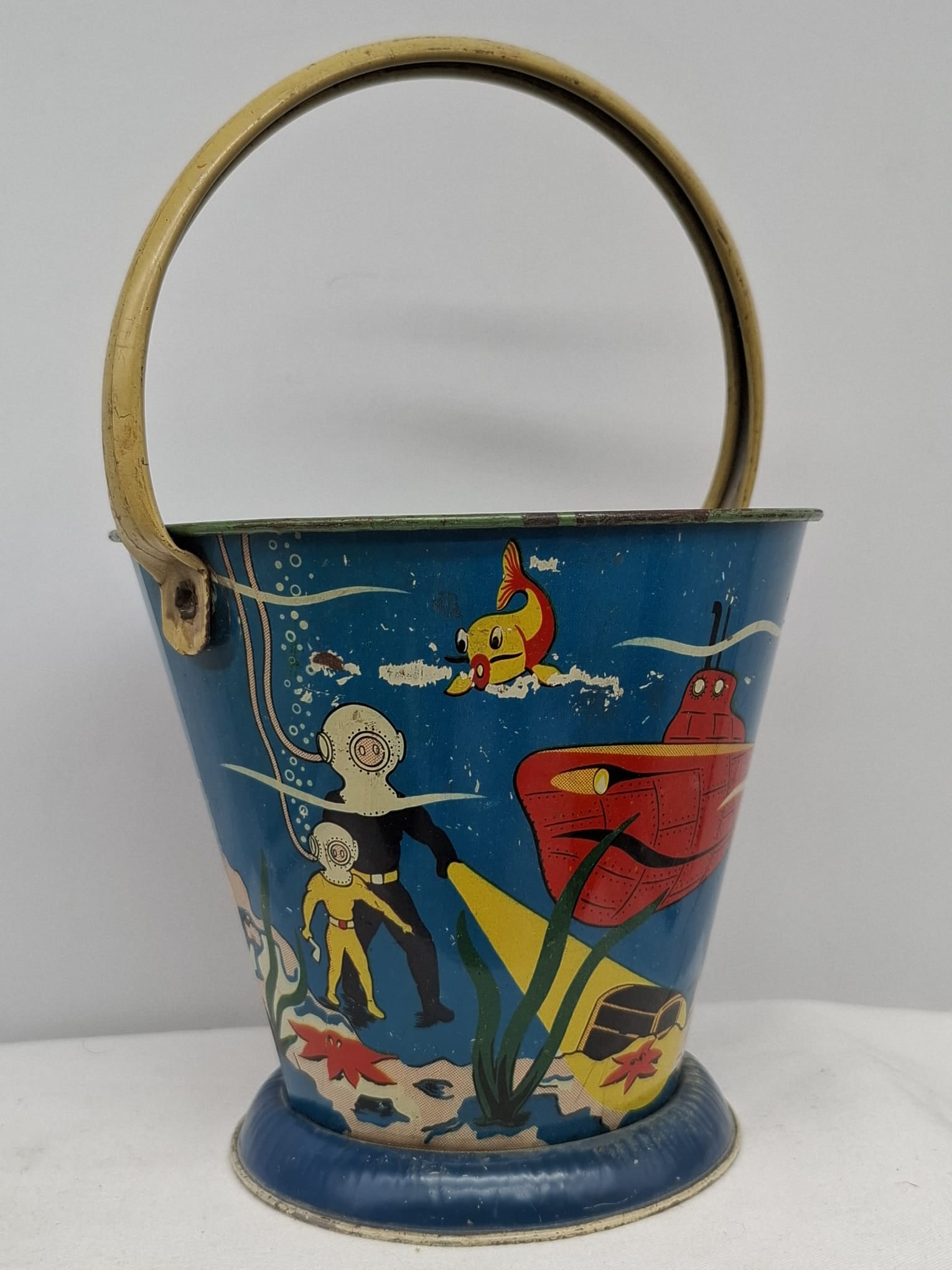 Early 20th Century Lithographed Tin Sand Pail – From Extensive European Collection: A charming and increasingly scarce early 20th century lithographed tin sand pail, exemplifying the colorful and imaginative design of classic seaside toys. This piece features vibrant period lithograp