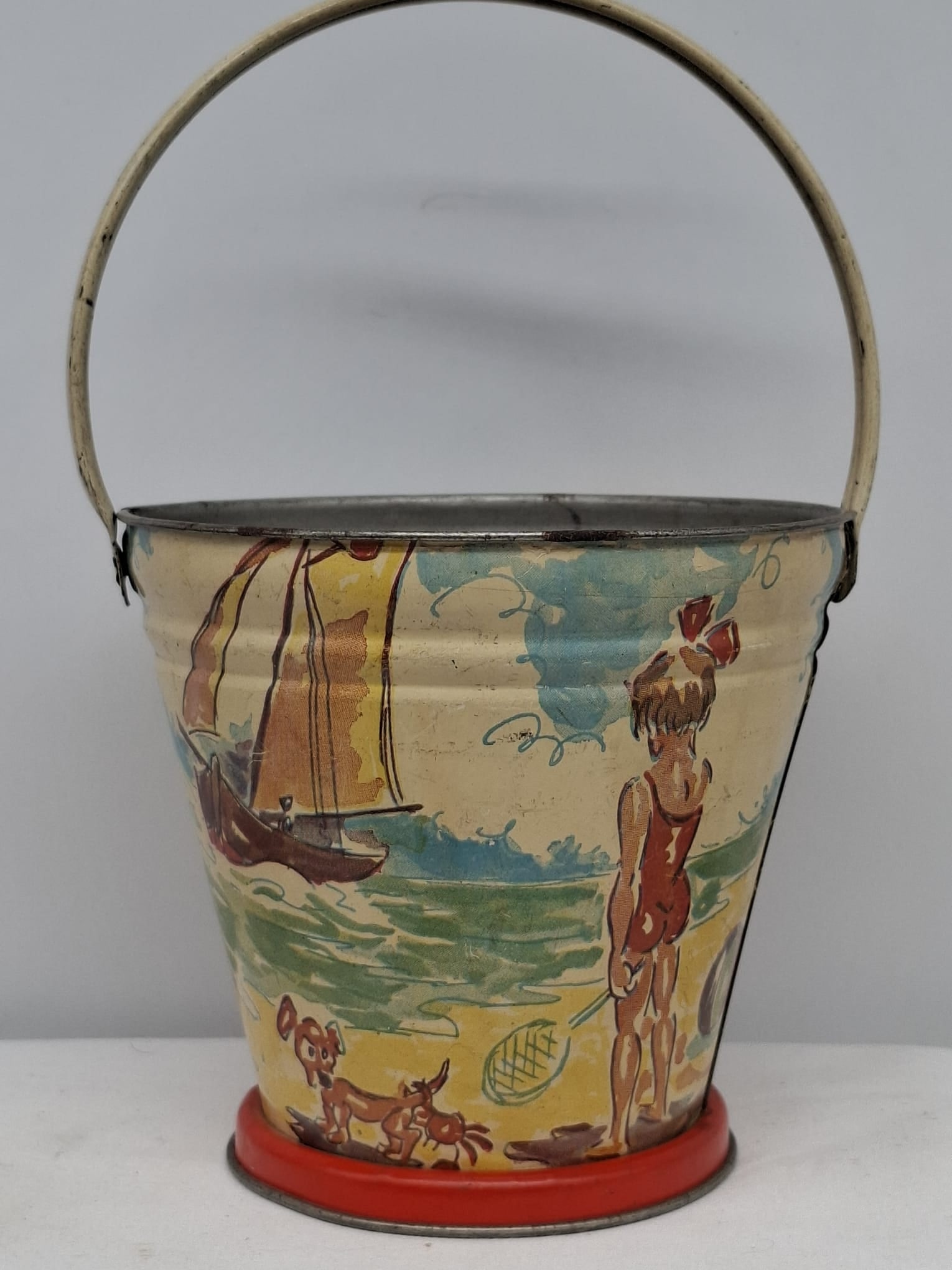 Early 20th Century Lithographed Tin Sand Pail – From Extensive European Collection: A charming and increasingly scarce early 20th century lithographed tin sand pail, exemplifying the colorful and imaginative design of classic seaside toys. This piece features vibrant period lithograp