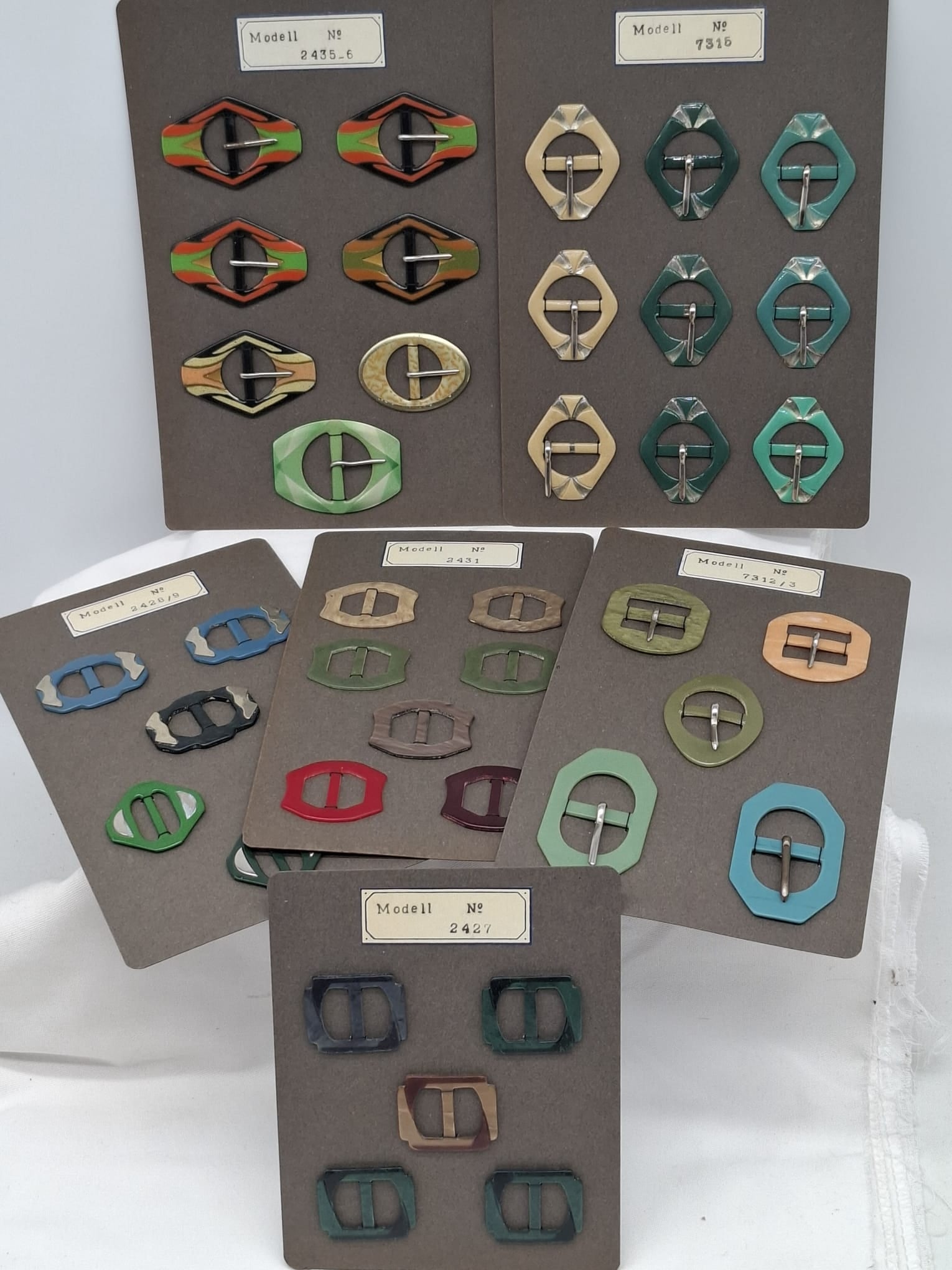 Lot of 39 Vintage Celluloid or Bakelite Belt Buckles on Original Store Cards – Czech or German: An attractive and unusual lot of vintage belt buckles, comprising a total of 39 examples still mounted on six original store display cards. Likely of Czech or German origin, these buckles are made of