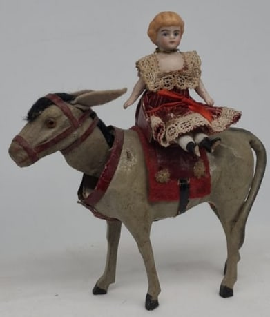 Charming 19th Century German Papier-Mâché Donkey Nodder with Bisque Doll Rider: A delightful and scarce 19th-century German toy featuring a papier-mâché composition donkey nodder with wooden legs, complete with its chair saddle and original bisque-headed doll rider. Rich in cha