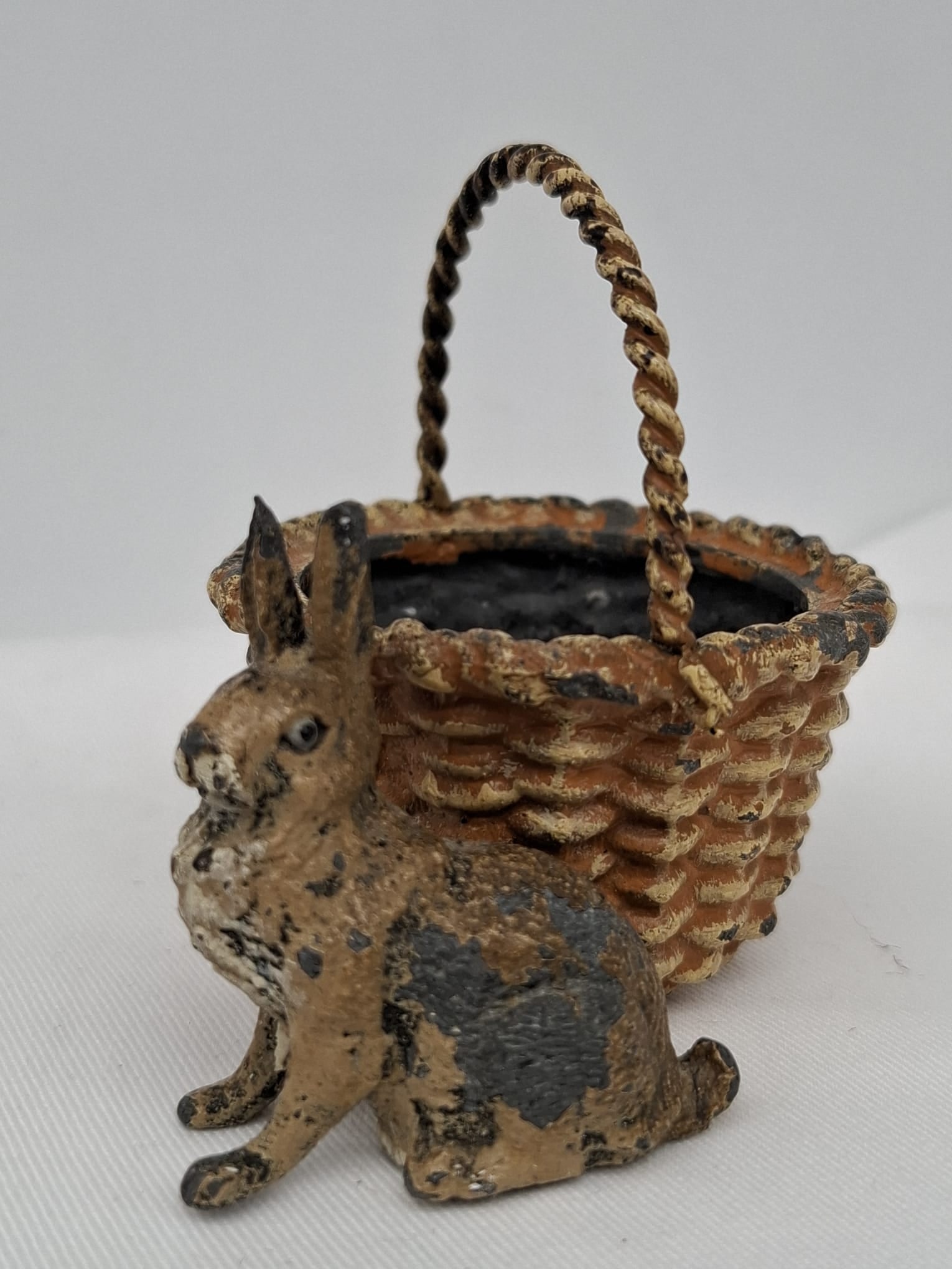 Rare German Lead Rabbit with Basket – Painted Figural Form, Possibly Pincushion or Candy: A very rare and charming German figural lead rabbit, dating to the late 19th or very early 20th century. Modeled seated beside a basket, this delightful piece is crafted in the same style as the highl