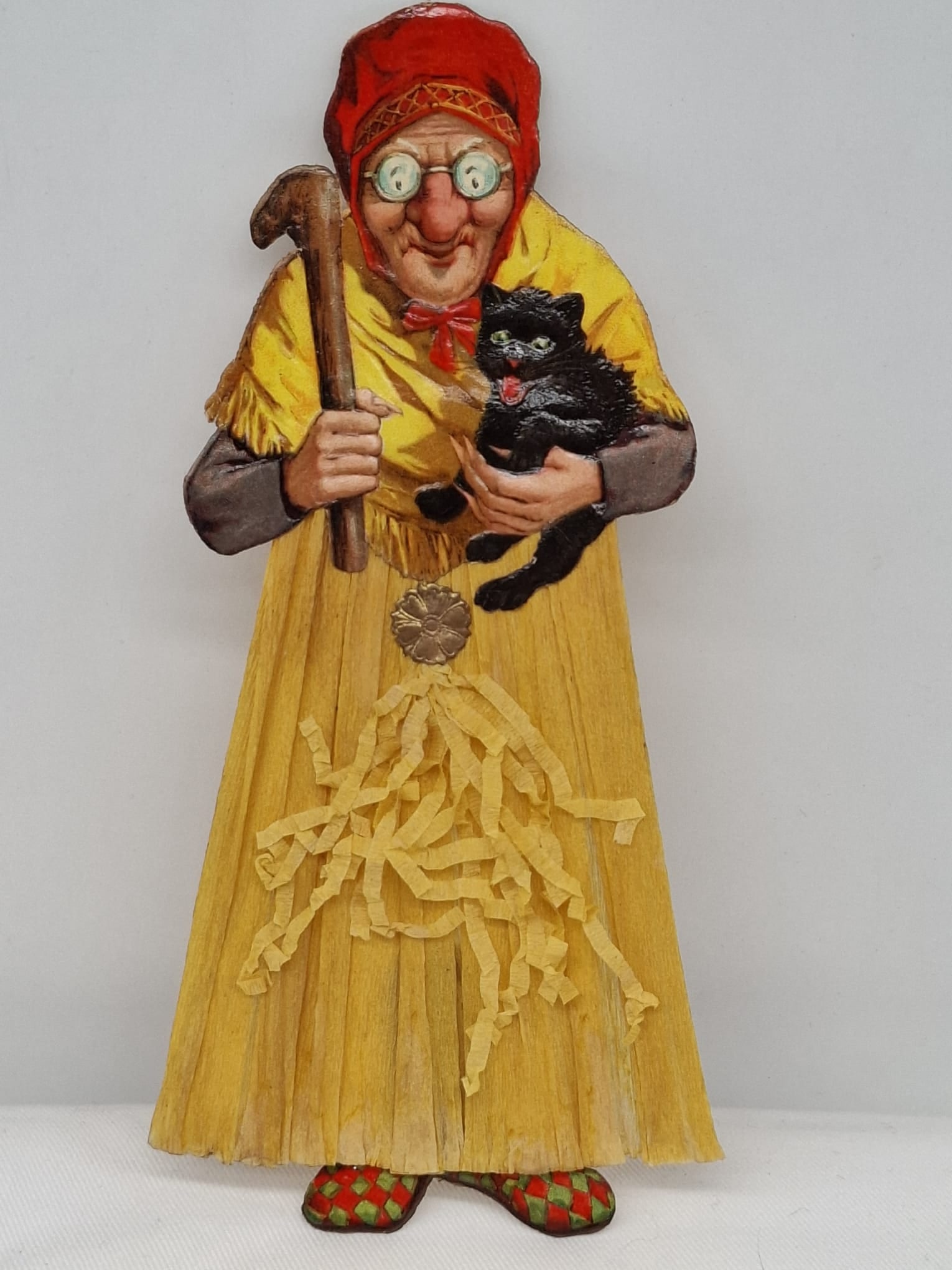 1920s Crepe Paper Halloween Witch Decoration: A highly desirable and authentic 1920s Halloween witch figure, dating to the celebrated Golden Age of Halloween decorations. This charming piece is crafted from crepe paper and features a vividly chro