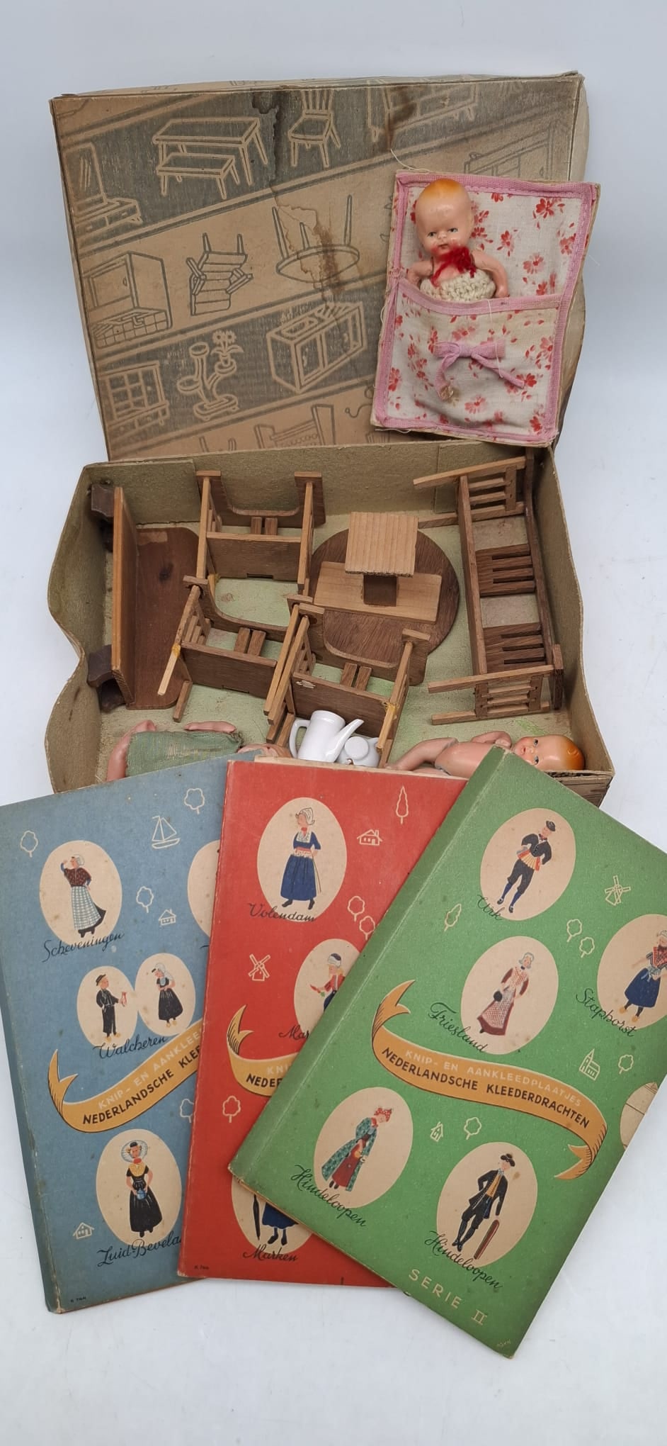 1920s–1930s Dollhouse Furniture Set with Original Box, Dolls & Dutch Provincial Paper Dolls: Charming and unusual grouping of early 20th-century children's play items, centered around a dollhouse furniture set dating to the 1920s–1930s and retaining its original box. The furniture represent