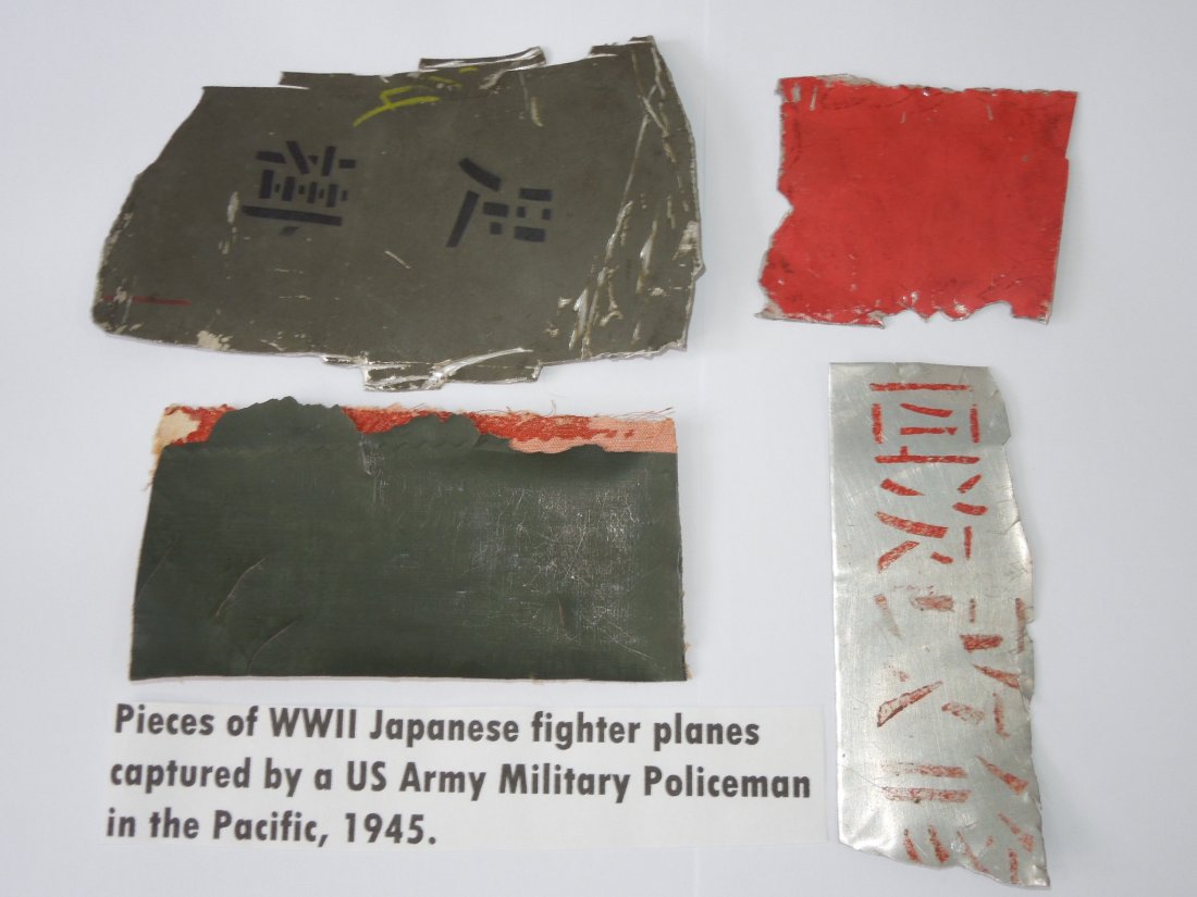 WWII Pieces of Shot Down Japanese Planes: Lot of four pieces cut from destroyed Japanese Planes brought home by Sgt. Milton Berkheimer, a Military Police Sergeant who served in Europe and the Pacific. Three metal, one fabric.