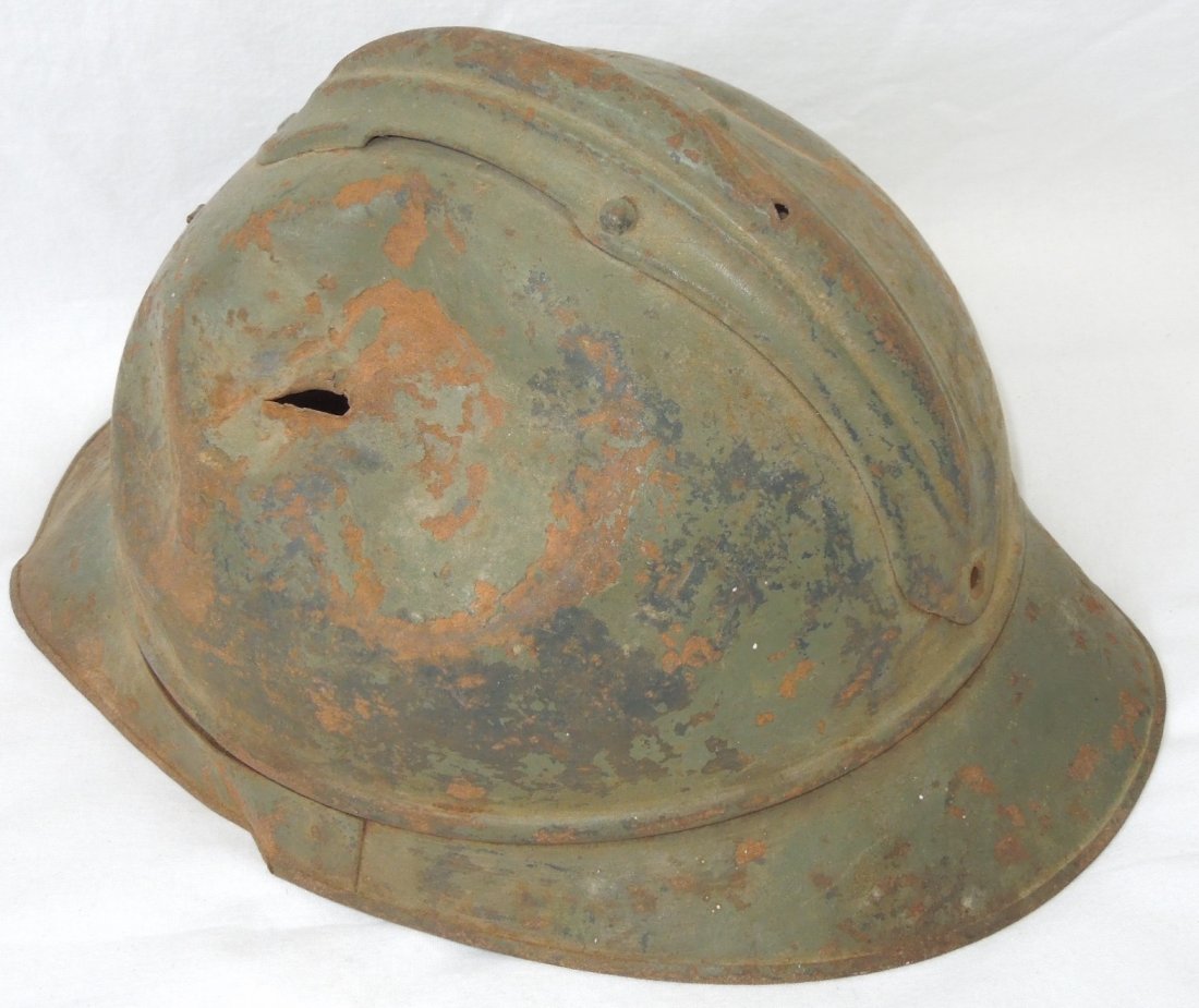 WWII French Adrian Military Helmet Shrapnel Hole: Original WWII era French (?) Adrian style helmet with a shrapnel or bullet hole and large dent in one side, possibly an old dug up piece given the relic condition. The liner is gone and only one small