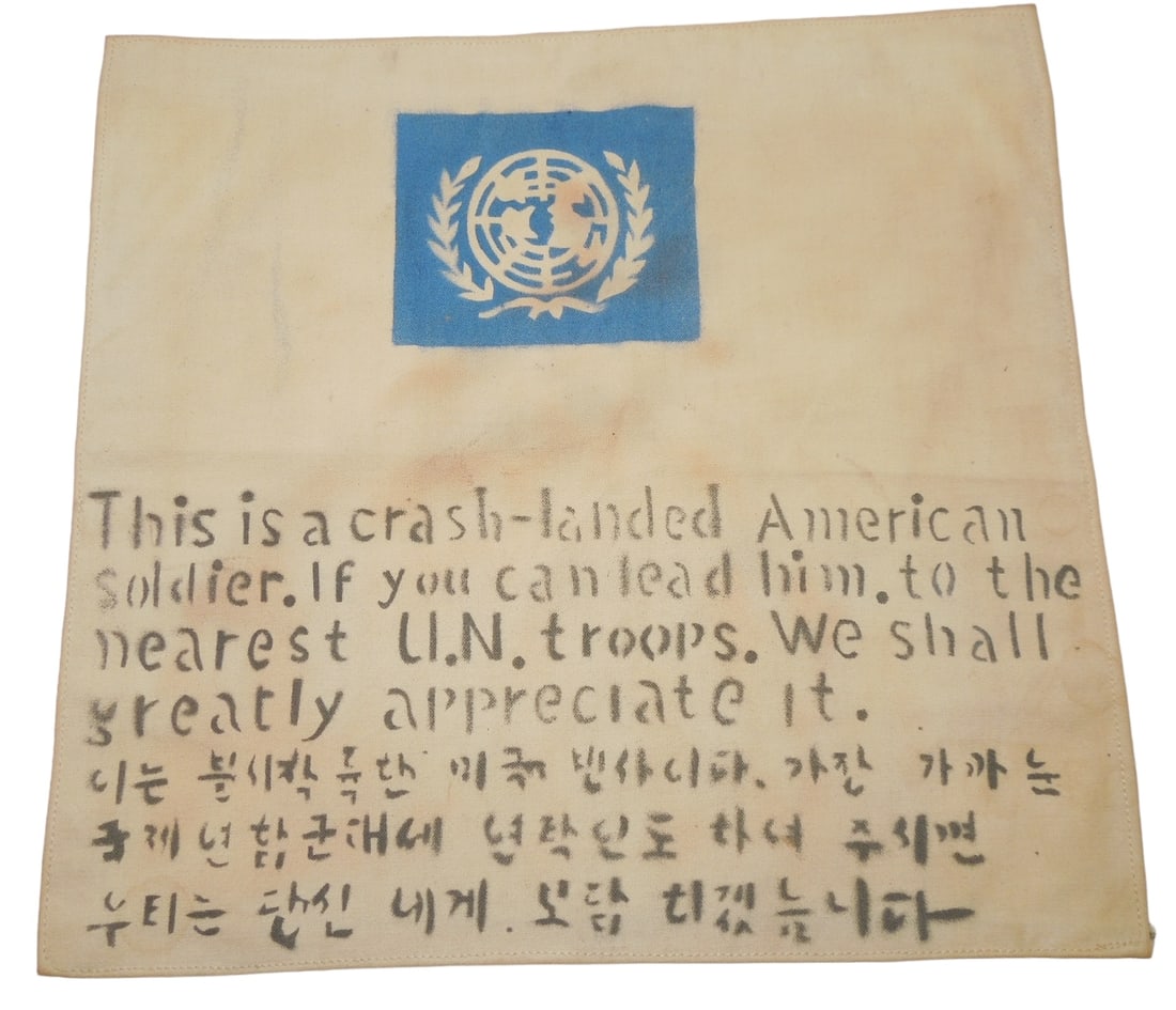 Korean War United Nations US Theater Made Cloth Blood Chit: Original cloth fabric piece designed to be sewn into aviator jackets during the Korean War, with stamped wording to assist them in case of emergency. Good condition with soiling consistent with age.
