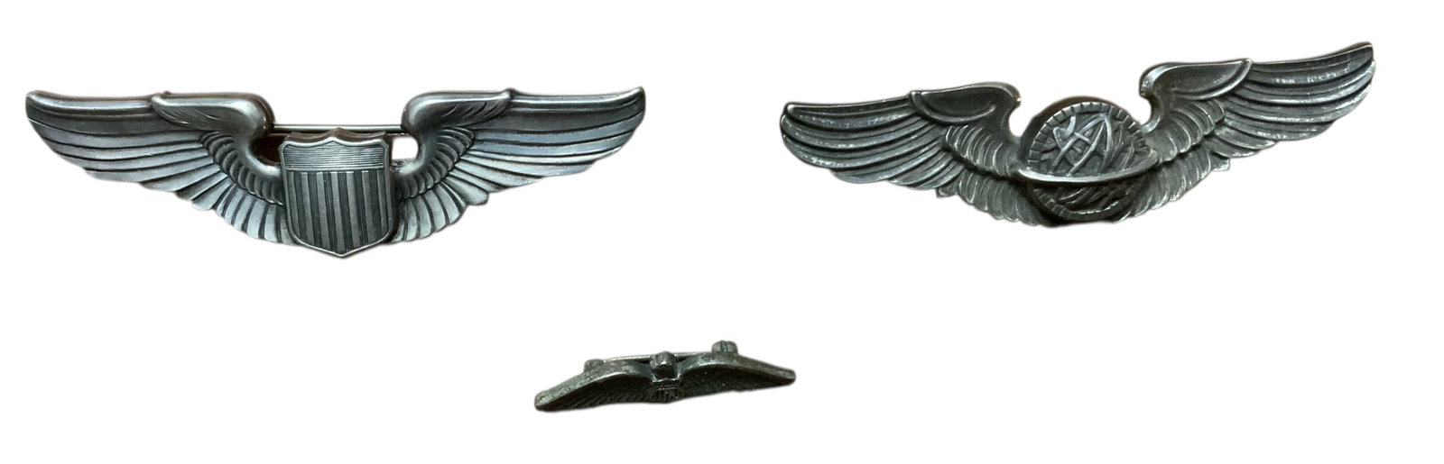 WWII Era Army Air Forces Pilot, Navigator & AAF Civilian Instructor Wings Lot (3): (2) Pin backs and (1) clutch back. 2 of the pins are full size 3 inch and the other is 1.25 inches. The wings are marked with the following: Pilot Wing (STERLING), Navigator Wing (AMICO STERLING) & AA