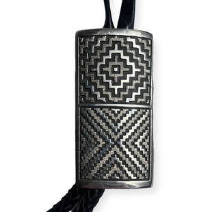 Large Dan Jackson Navajo Rug Pattern Silver Bolo Tie: Marked on back D.A. JACKSON. Circa 1990. The silver pendant measuring approx 3 1/4 x 1 3/4 inches. A fine example.