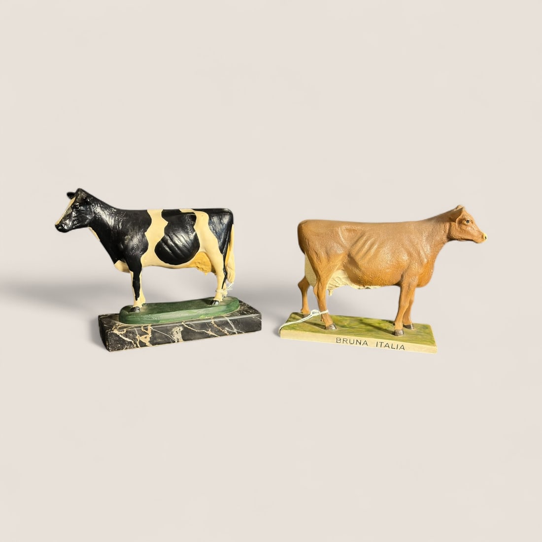 2 Cow Statues: A dairy cow and a Bruna Italia cow statues. 7 inch long x 5 3/4 tall, both good