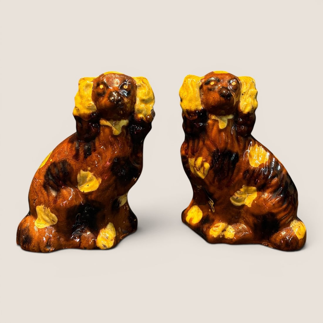 Pair of Pennsylvania Redware Spaniels: This pair of seated dog figurines is modeled in the style of Staffordshire spaniels and is attributed to the Bell pottery of Waynesboro, Pennsylvania. The figurines are hollow-cast from a coarse, redd