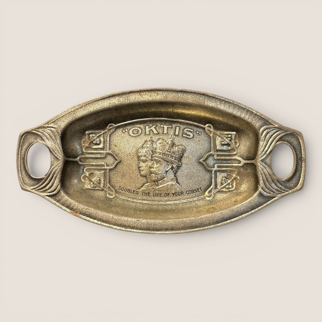 Art Nouveau Stamped Brass Oktis Advertising and Royal Commemorative Dish: An Art Nouveau stamped brass advertising dish produced for the Oktis brand, specifically commemorating the 1911 coronation of King George V and Queen Mary. The dish is of an elongated oval form with i