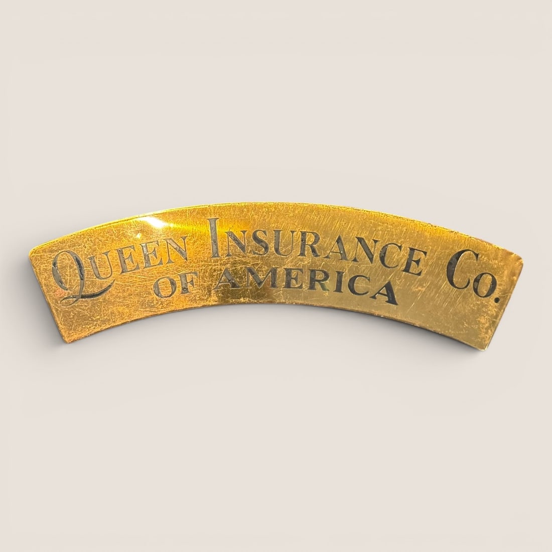 Antique Brass Queen Insurance Co. of America Nameplate: This antique advertising nameplate is constructed of brass and features a distinctive arc-shaped profile. The piece identifies the Queen Insurance Co. of America, a firm incorporated in New York in 18
