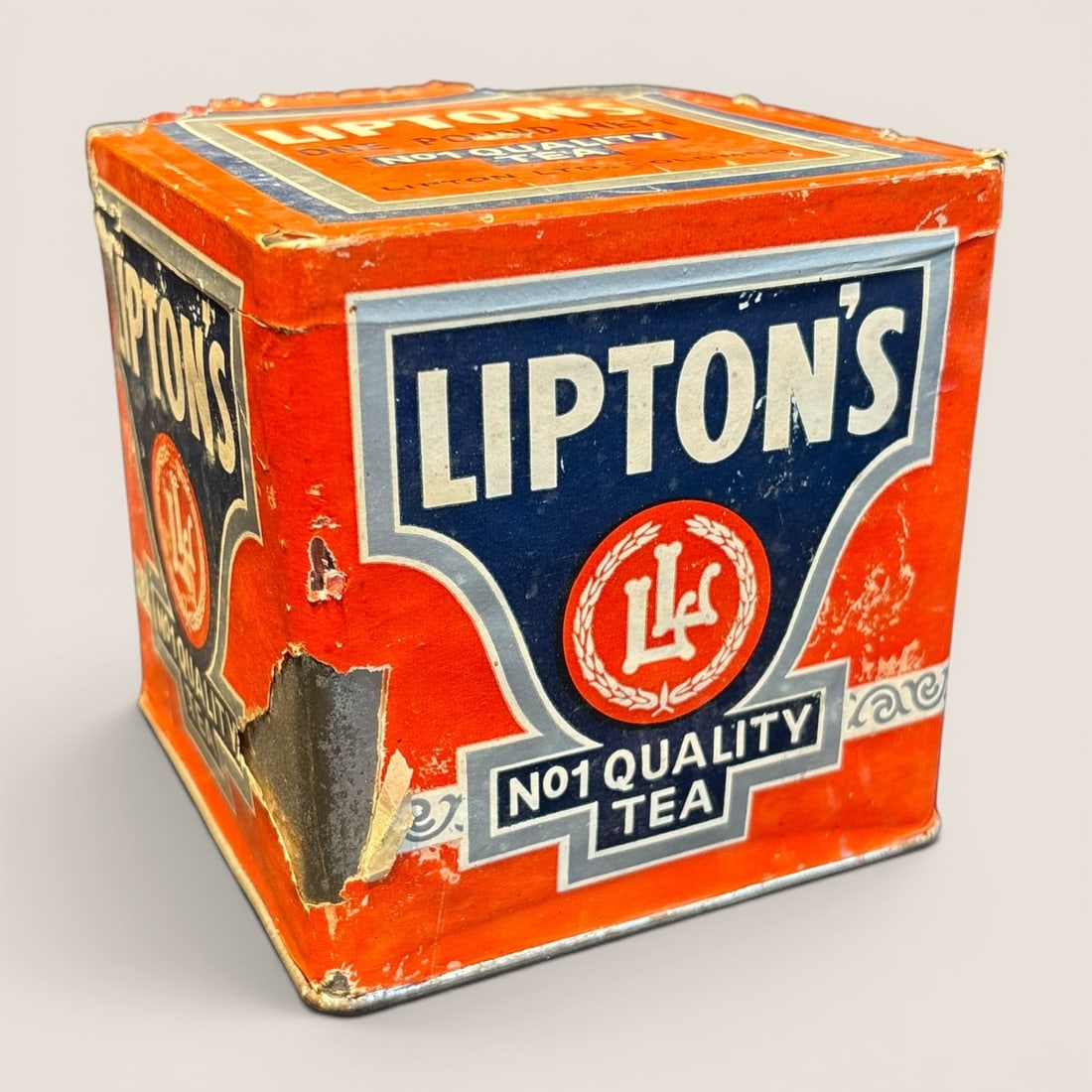 Antique Lipton's No 1 Quality Tea One Pound Paper Label Advertising Tin: An antique Lipton's Tea retail tin, square in form and constructed of metal with applied lithographed paper labels. The branding is set against a vibrant orange ground and features a blue shaped banne