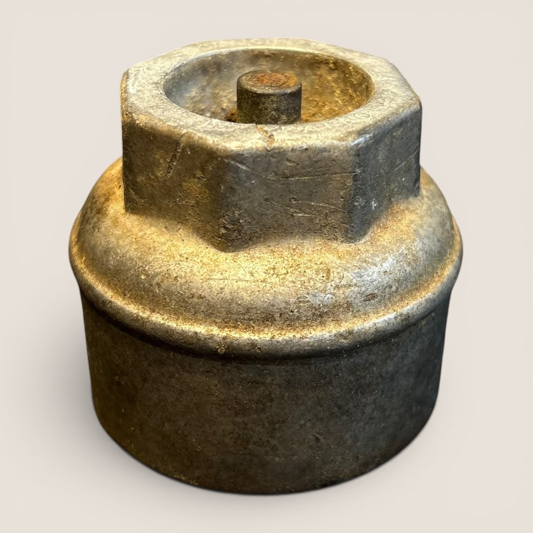 Vintage Cast Metal Automotive Hub Grease Cap: This item is a vintage automotive hub grease cap, likely manufactured in the early to mid-20th century. The component is made from a heavy cast metal alloy with a dull grey finish. The form consists
