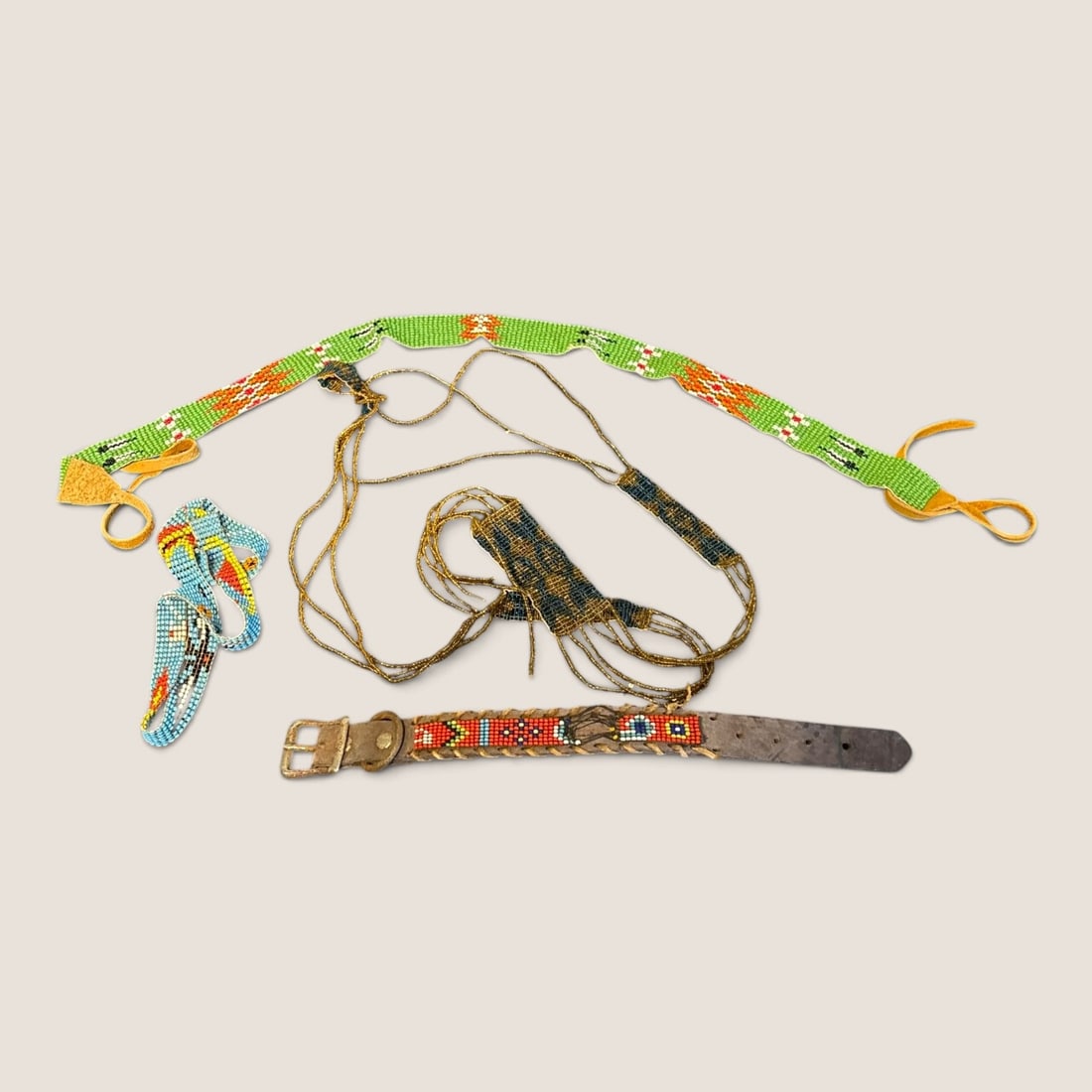 An Assortment of Beaded and Leather Fashion Accessories: This collection includes several hand-beaded accessories featuring geometric patterns and metallic accents. One piece is a multi-strand necklace composed of metallic bronze-tone seed beads with a cent