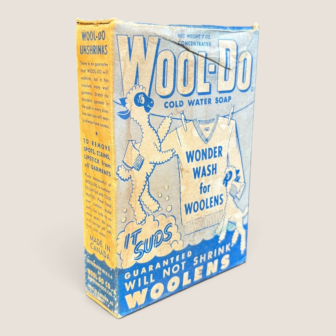 Vintage Wool-Do Cold Water Soap Cardboard Box: A mid-century Canadian-made printed cardboard box for Wool-Do Cold Water Soap. The packaging features a blue and white color scheme with a yellow side panel, prominently displaying an anthropomorphic 