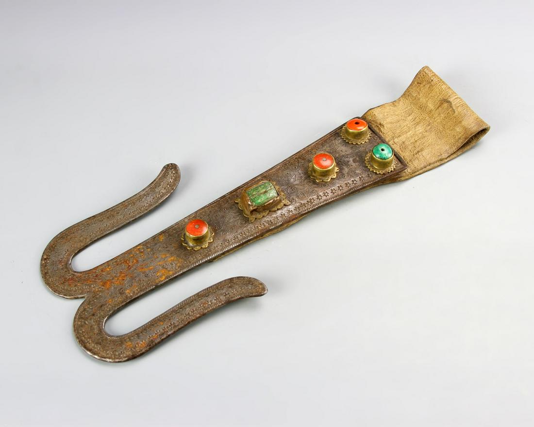 Chinese Tibetan Metal Ornament: China, 19th C., Tibetan metal ornament, with inlays of turquoise and coral stones, textile flap on one end, splitting at other end into two curving metal pieces. Length 12 in.