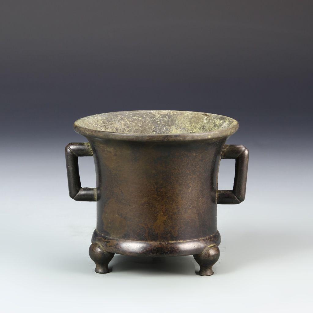 Chinese Bronze Censer: China, 19th C., bronze tripod censer, with an elongated body, flanked by a handle on each side, finishing in a wide, flared rim, with patina, mark on base. Width 4 in., Height 5 1/2 in.