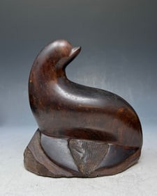 A vintage collectible hand-carved ironwood sea lion sculpture: This vintage collectible is a hand-carved ironwood sea lion sculpture, likely originating from Mexico. It features polished, dense wood that gives it a smooth, dark finish. These artistic figurines we