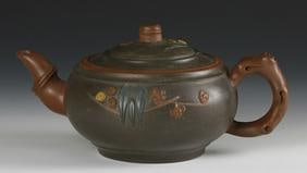 Chinese Yixing Teapot: China, 20th C.,green teapot with brown and yellow embellishments; handle, spout and lid in the form of branches, marking on base. Width 7 1/2 in., Height. 3 1/2 in.