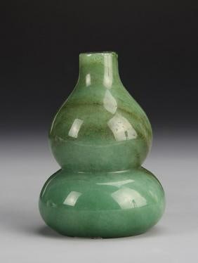 Antique Chinese Jadeite Gourd: China, antique jadeite gourd, with tapered neck, and flat base, in a mottled light green hue, with striations in the stone, and smooth carved surface. Height 3 in.