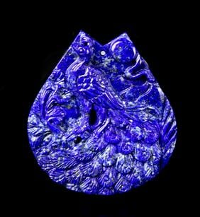 Chinese Lapis Pendant: China, lapis pendant, tear drop formed body with plain underside, carved decoration of a large peacock with natural blue and beige colors throughout. Length 2 1/4 in., Width 2 in.