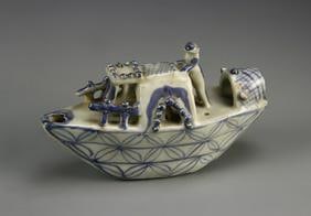 Antique Chinese Blue And White Boat: China, Qing Dynasty, blue and white boat, carved with details of the boat structure and the single figure standing on it, with a crisscross blue design on the sides. Length 6 1/2 in.