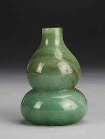 Antique Chinese Jadeite Gourd: China, antique jadeite gourd, with tapered neck, and flat base, in a mottled light green hue, with striations in the stone, and smooth carved surface. Height 3 in.