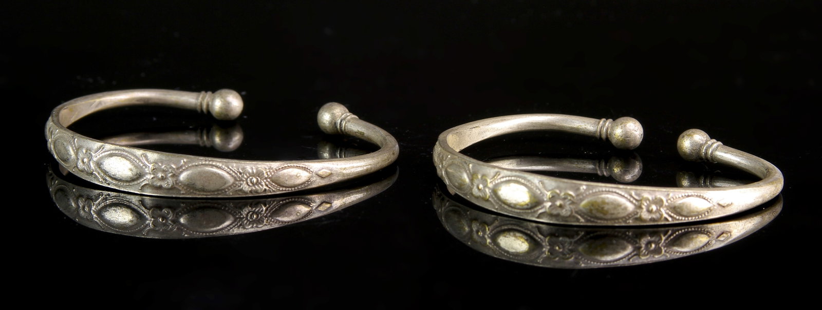 Pair of Chinese Silver Bangles: China, 19th C., pair of silver bangles, with floral pattern in raised relief, with a split opening, and a smooth, high shine surface. Diameter 2 7/8 in.