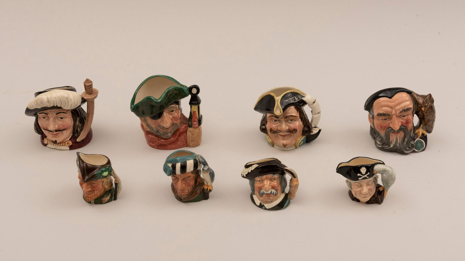 Eight Royal Doulton Character Jugs: Eight Royal Doulton Character Jugs To include: Sancho Panca The Falconer Long John Silver Capt. Henry Morgan Smuggler Porthos Robin Hood and Merlin.