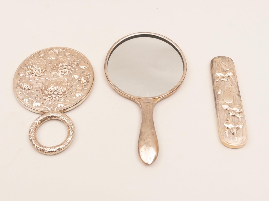 CHINESE EXPORT SILVER HAND MIRROR: Round with handle, dragon in high relief, together with unmarked plated silver mirror handled frame, chrysanthemum relief and brush frame with lilies, 20th century. Lengths:10", 8 " and 6 3/4 inches.