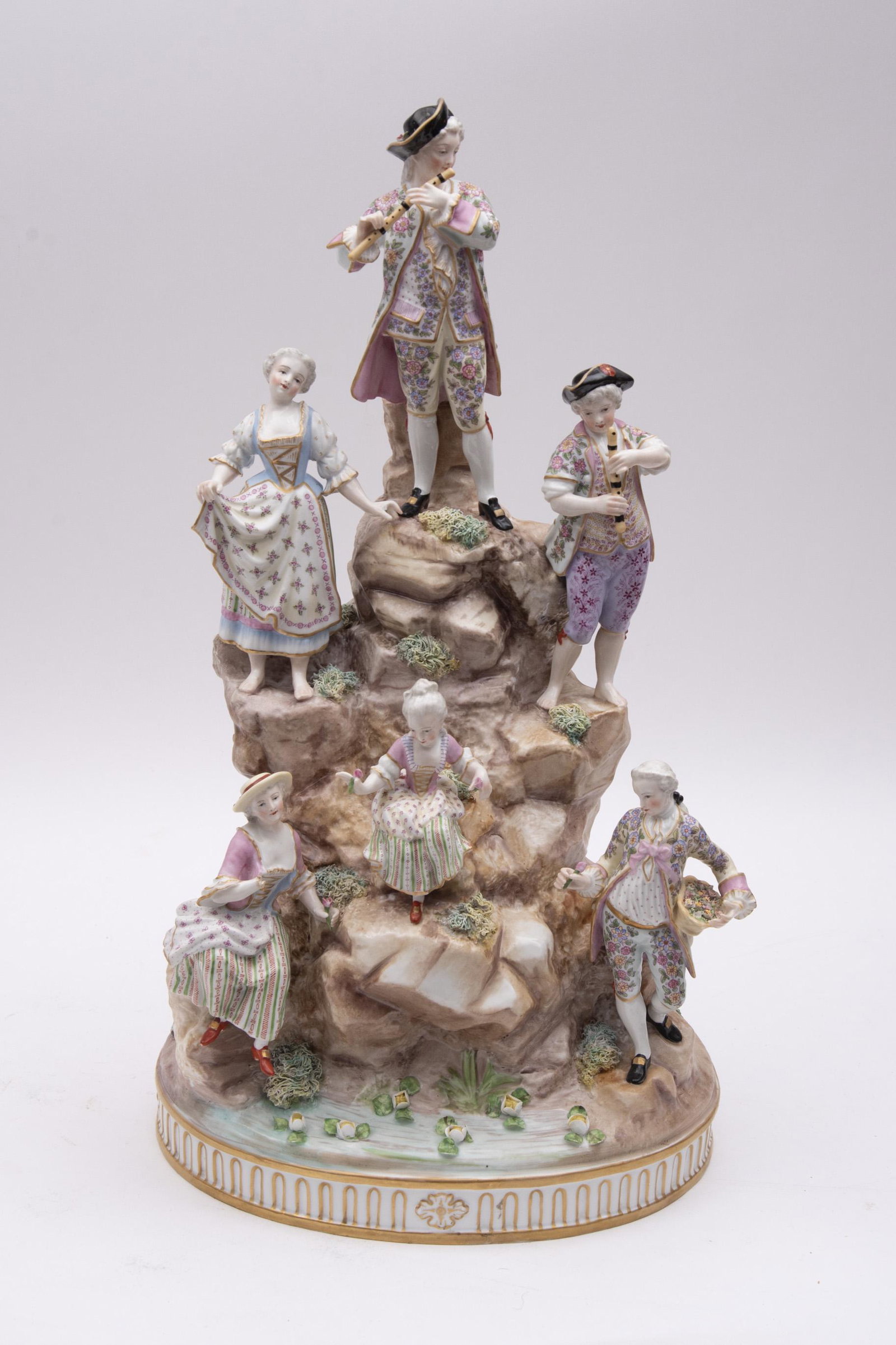 19th Century Meissen Style Porcelain Centerpiece 22": 19th Century Meissen Style Porcelain Centerpiece Large 6 figure grouping depicting multiple figures on a rocky mountain base. Figures holding baskets and bundles of flora and the central figure playin