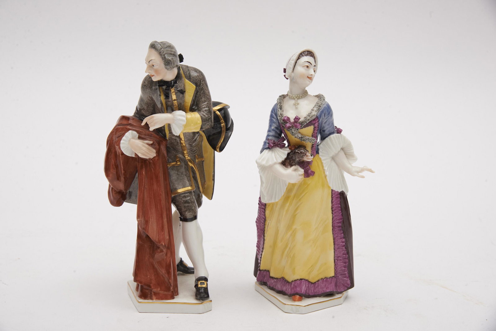 A Fine Pair of Nymphenburg Porcelain Figurines, a Lady: A Fine Pair of Nymphenburg Porcelain Figurines, a Lady and a Gentleman Both figures well modelled, the lady with long flowing sleeves and skirt, holding her dog; the gentleman with hat/cape and a long