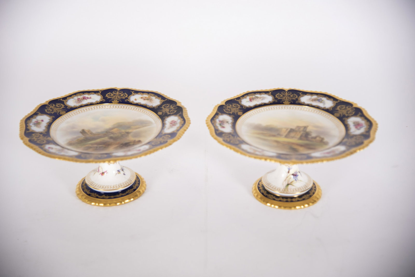 Pair of Antique Royal Worcester Painted Porcelain: Pair of Antique Royal Worcester Painted Porcelain Compotes A lovely pair of footed Worcester compotes painted with castle scenes by J. Stinton. Both compotes with cobalt background, highlighted with g