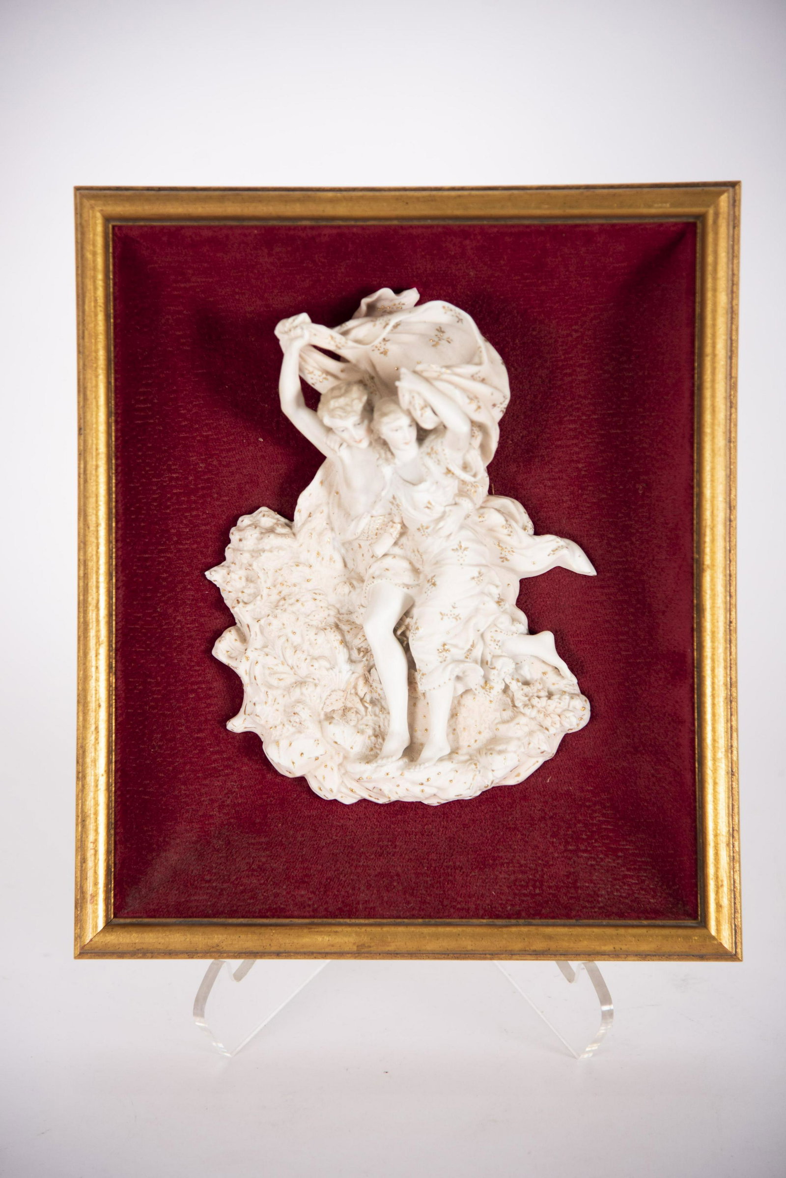 A Continental Porcelain Figure Group Plaque: A Continental Porcelain Figure Group Plaque The porcelain plaque depicting a young maiden and man running with a scarf, highlighted with gilded details. Now framed in a shadow box. Framed size 11"