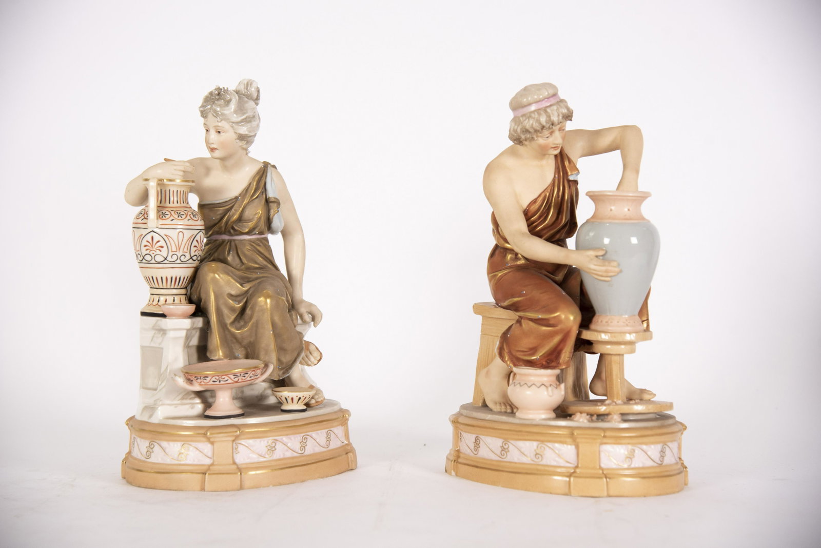 Pair of Royal Dux Neoclassical Design Statues height:: Pair of Royal Dux Neoclassical Design Statues Pair of antique statues depicting a man and a woman working on pottery vessels. height: 12 inches