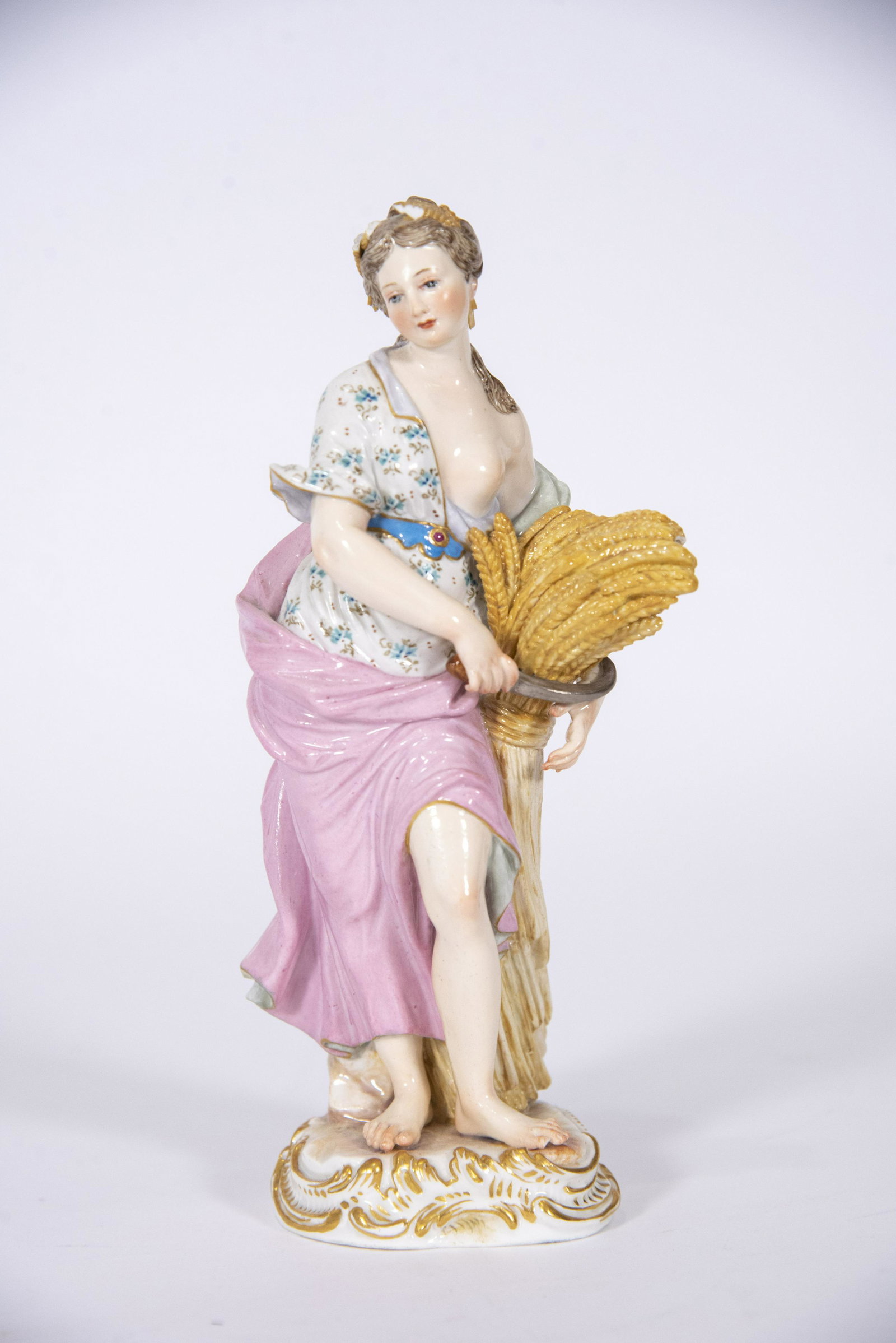 Meissen Porcelain Figure, Emblematic of Autumn: Meissen Porcelain Figure, Emblematic of Autumn figure of a maiden, emblematic of Autumn. The figure in flowing robes and floral painted blouse. Holding a gathering of wheatsheaf and sickle. Blue cross